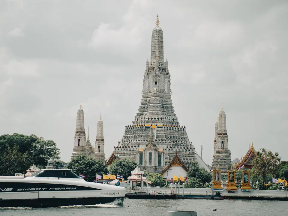 Stunning view of Wat Arun temple and Chao Phraya River in Bangkok, Thailand with a ferry boat