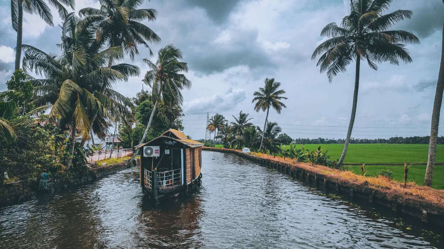 Scenic houseboat on a tranquil canal surrounded by lush palm trees in Kerala, India