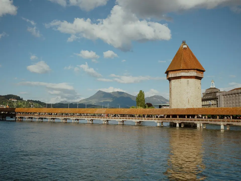 Scenic view of the historic Chapel Bridge and tower in Lucerne, reflecting in the Reuss River on a sunny day