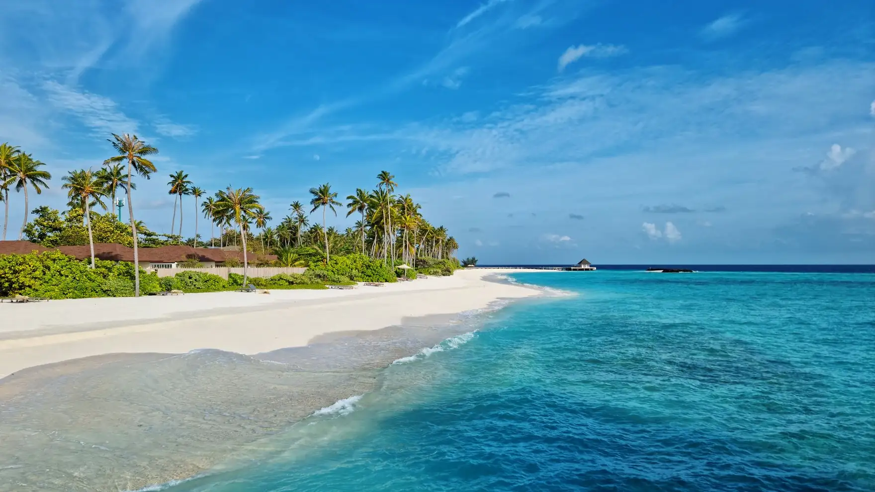 Experience the serene beauty of Maldives with turquoise waters and white sandy beach under a clear blue sky