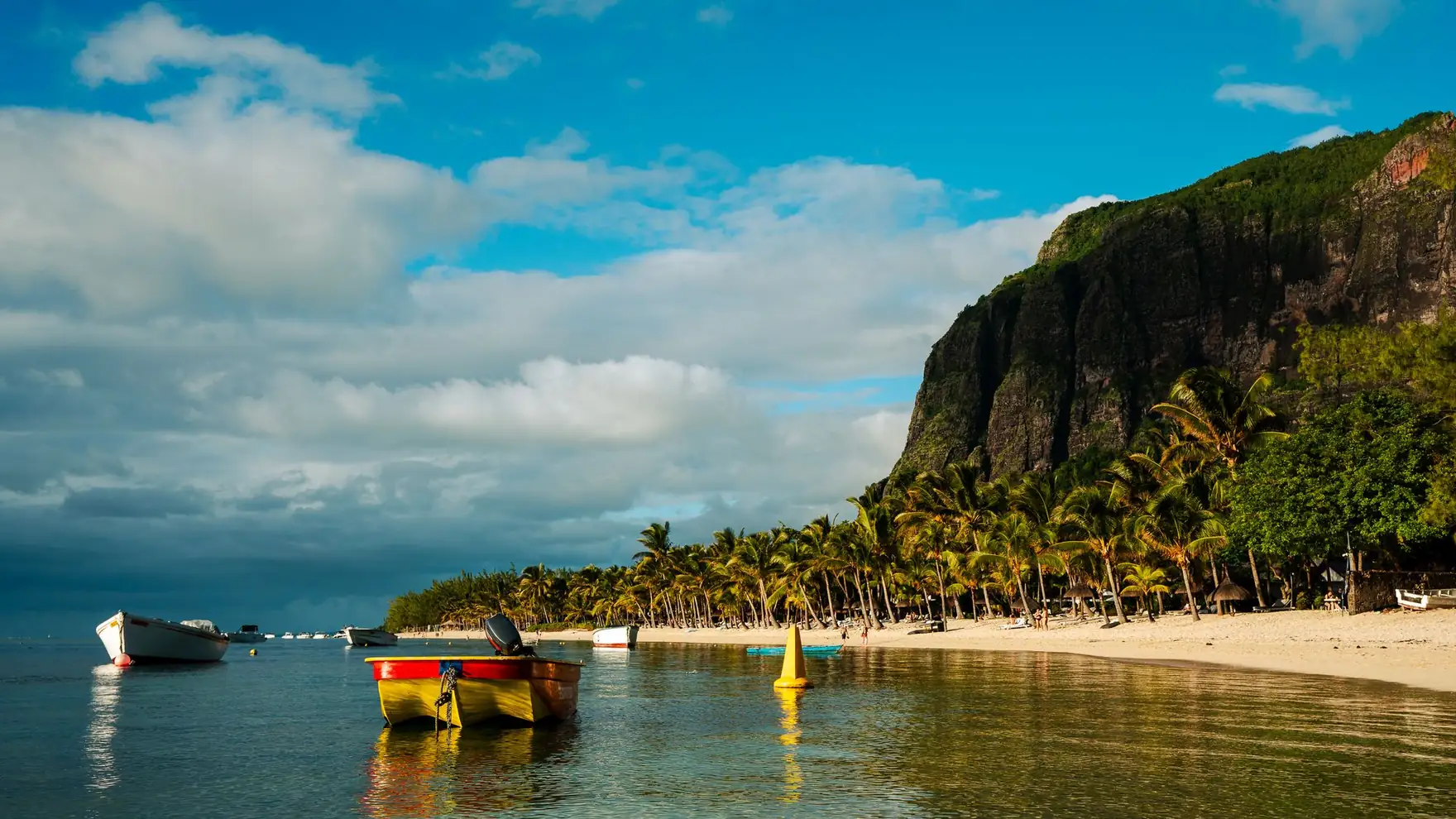 Serene beach scene with palm trees and boats at Le Morne, Mauritius during a sunny day