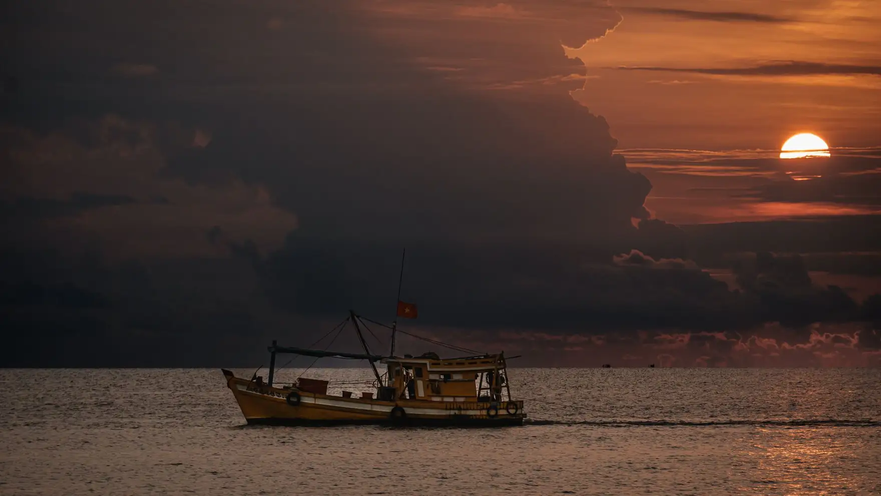 A fishing boat sails on the sea at sunset, captured in Phu Quoc, Vietnam