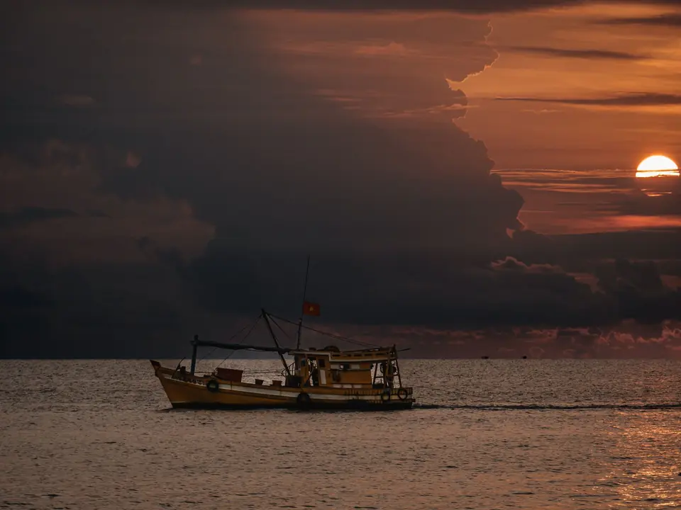 A fishing boat sails on the sea at sunset, captured in Phu Quoc, Vietnam