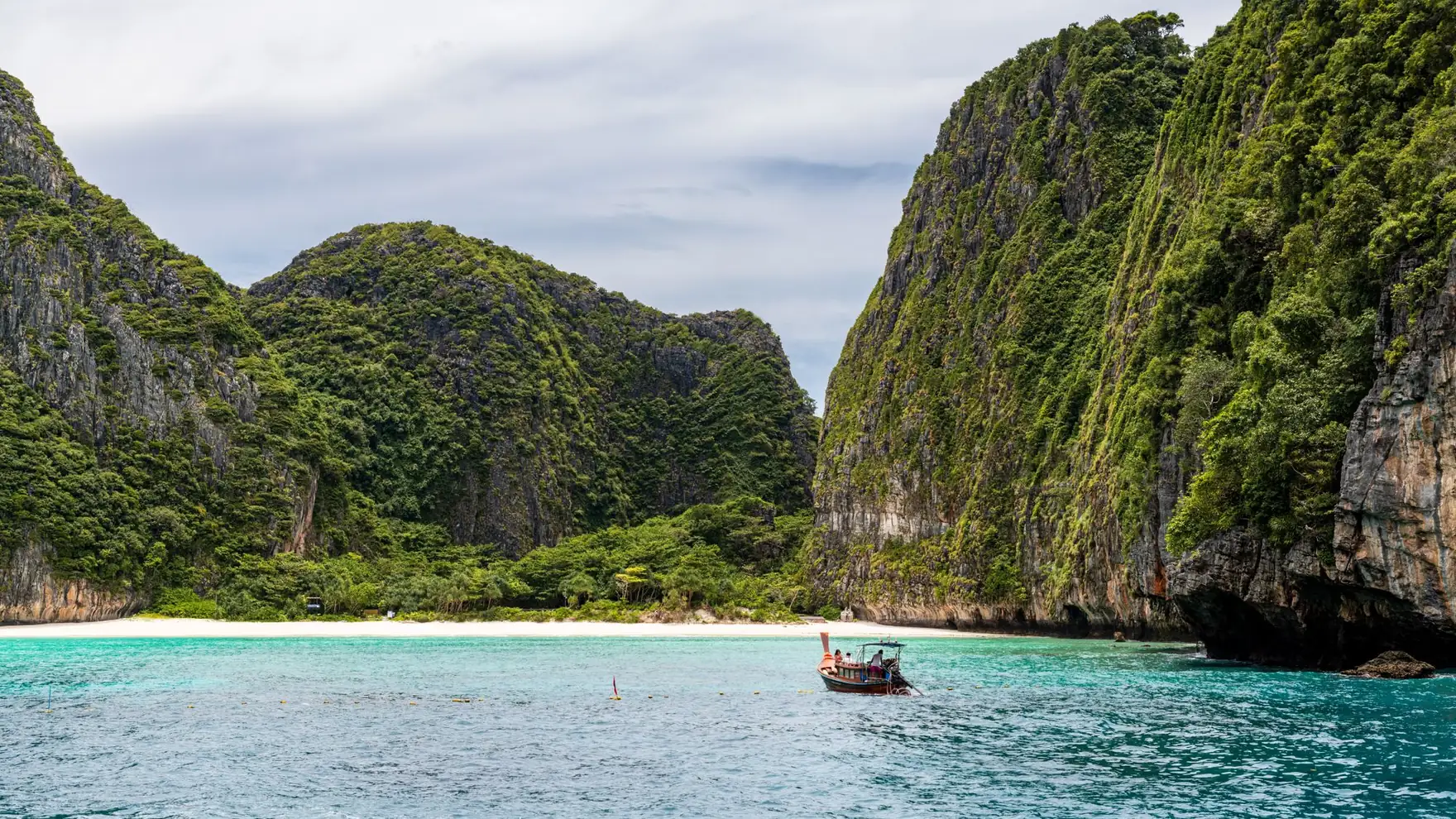 Idyllic view of a traditional boat against limestone cliffs and turquoise waters in Phuket, Thailand