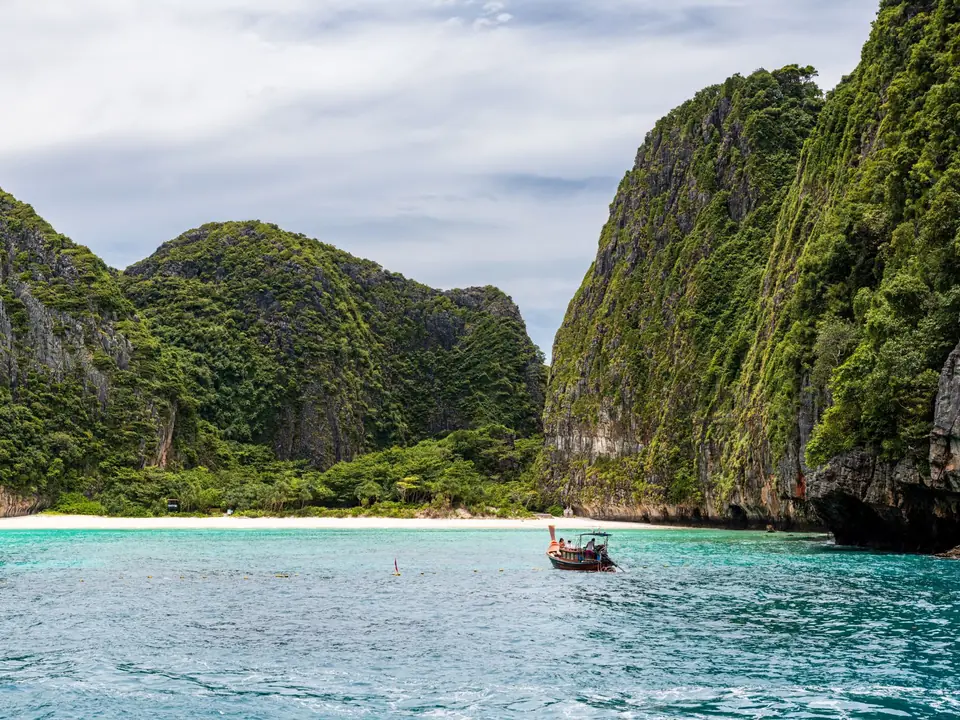 Idyllic view of a traditional boat against limestone cliffs and turquoise waters in Phuket, Thailand