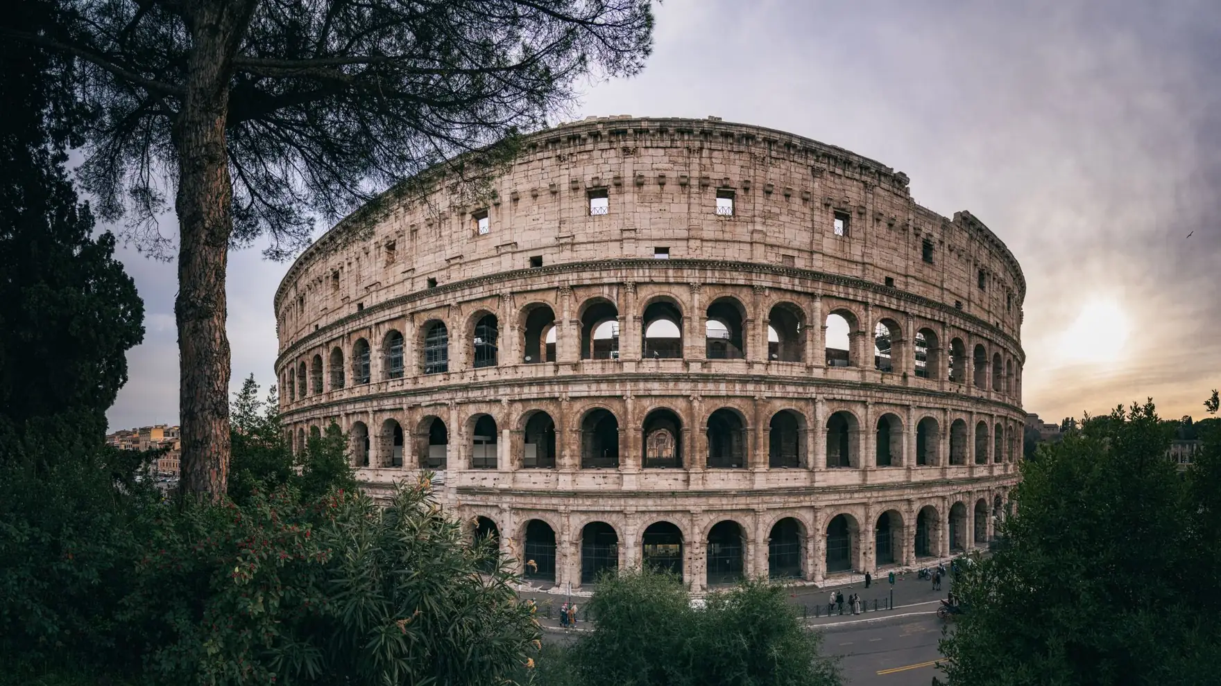 Captivating wide-angle shot of Rome's iconic Colosseum with a serene sunset backdrop