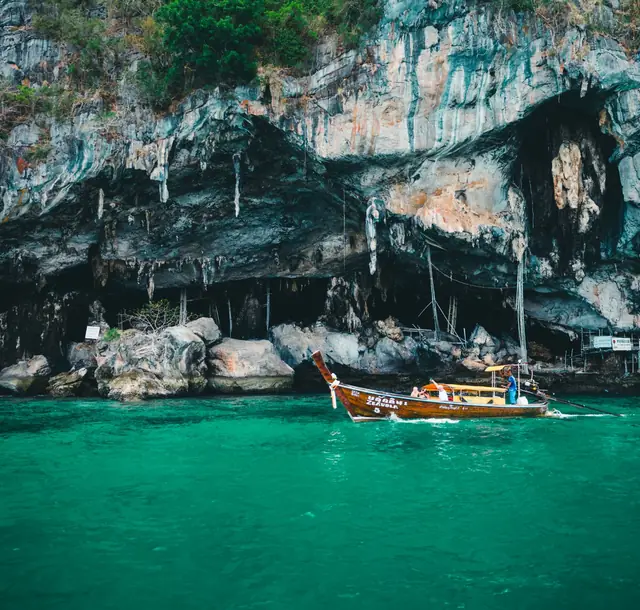 Explore the stunning limestone cliffs of Phuket with a traditional longtail boat on emerald waters