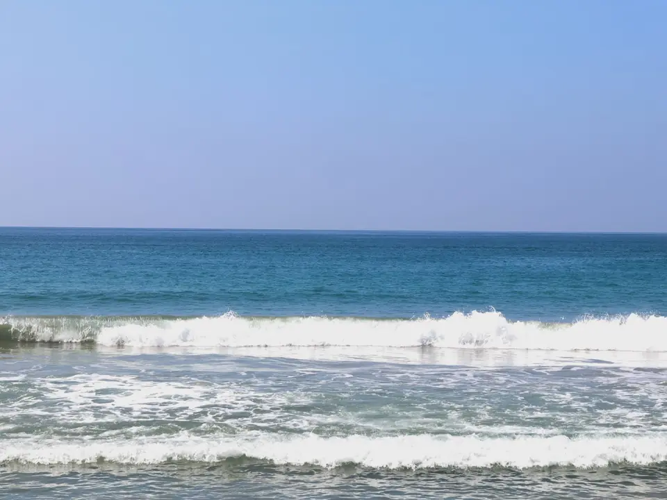 Peaceful ocean waves gently crashing at Varkala Beach, Kerala, India under a clear blue sky