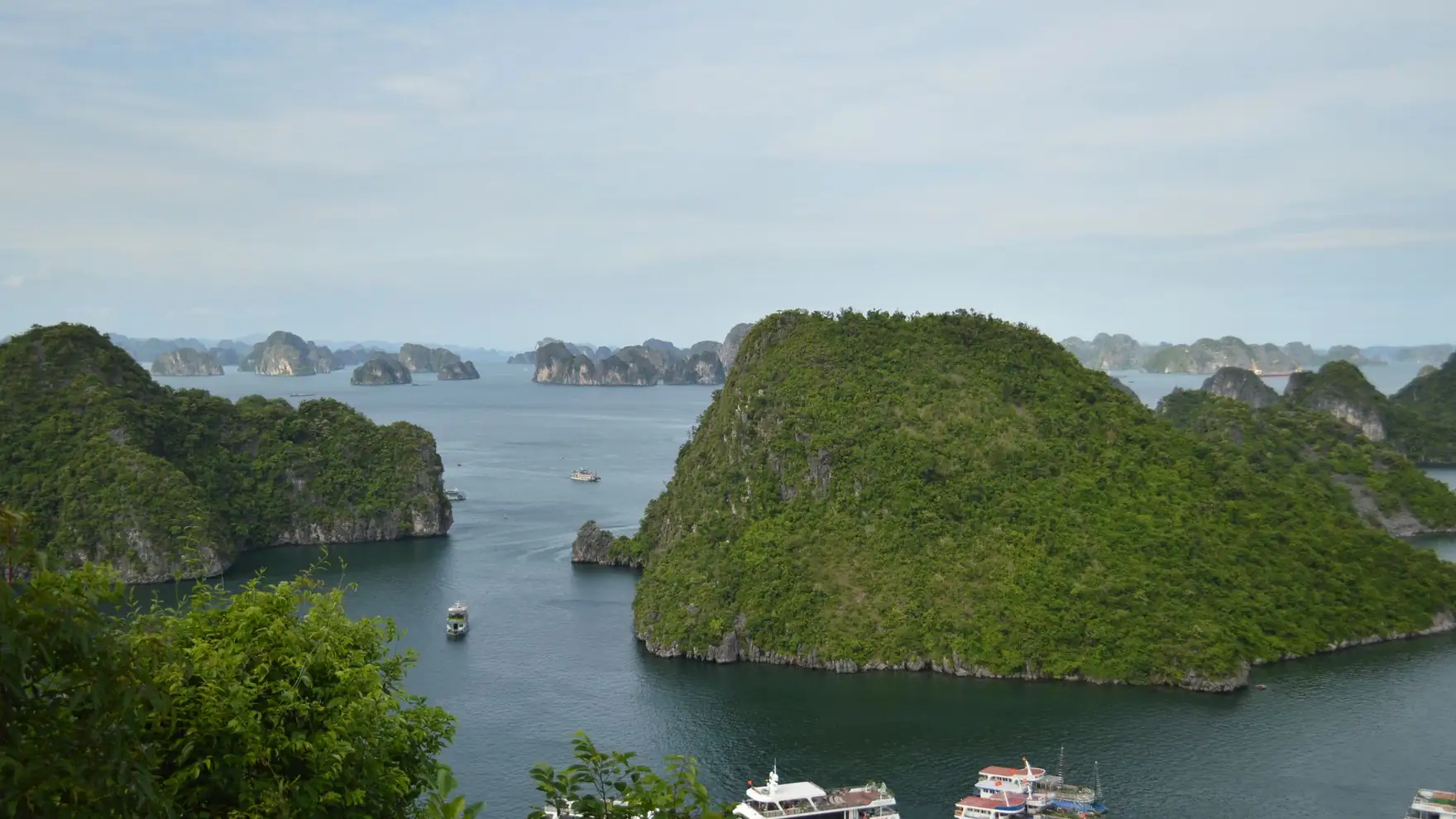 A breathtaking view of Ha Long Bay featuring limestone islands and tour boats on a calm day