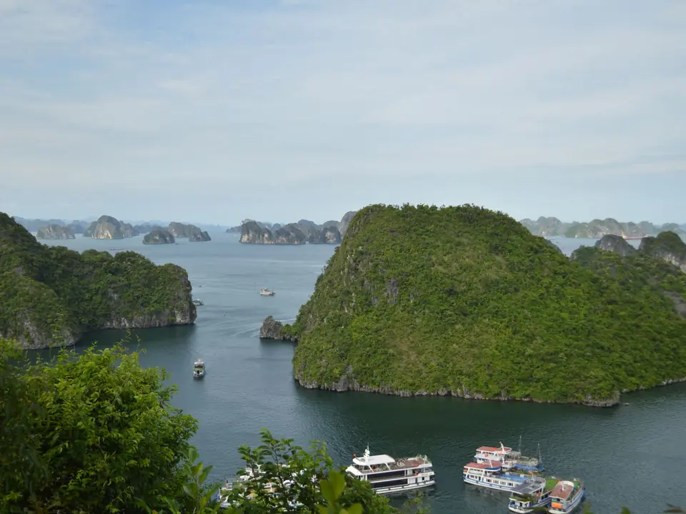 A breathtaking view of Ha Long Bay featuring limestone islands and tour boats on a calm day