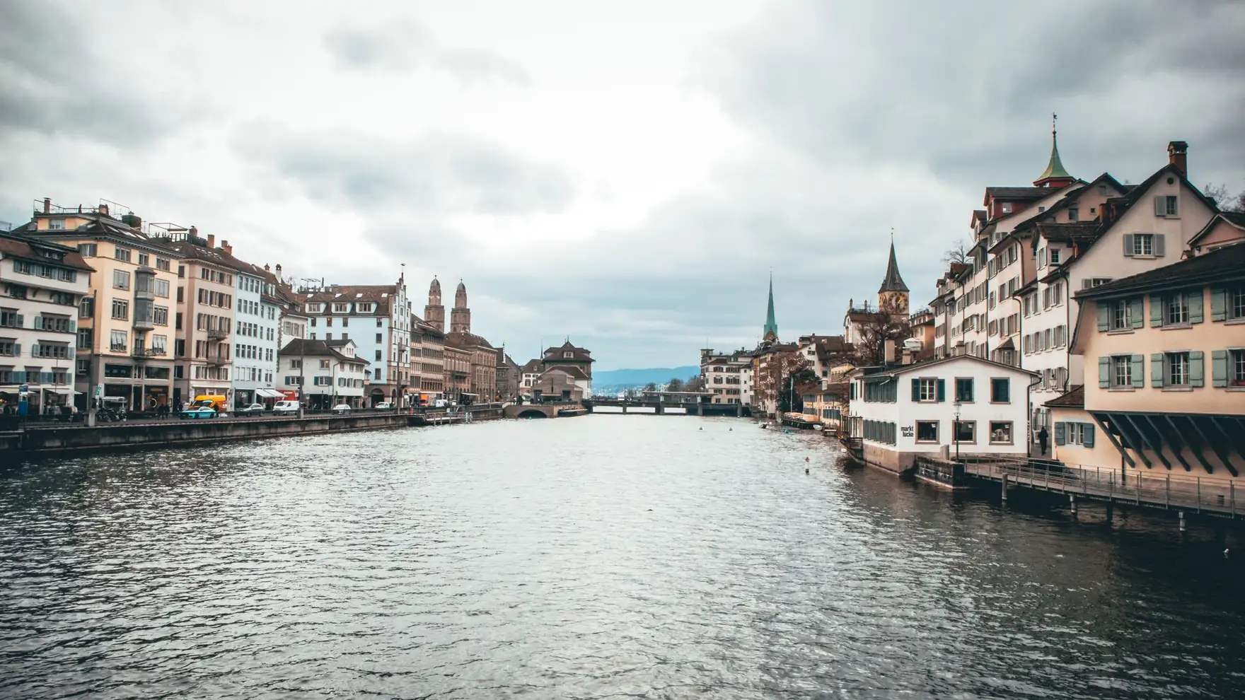 Scenic view of Zurich's historic buildings along the Limmat River under a cloudy sky