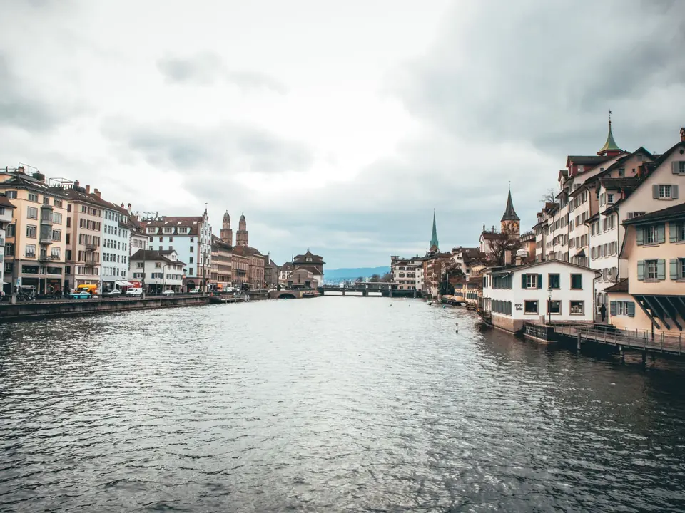 Scenic view of Zurich's historic buildings along the Limmat River under a cloudy sky